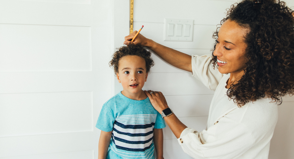 Mom measuring her son's height with a ruler