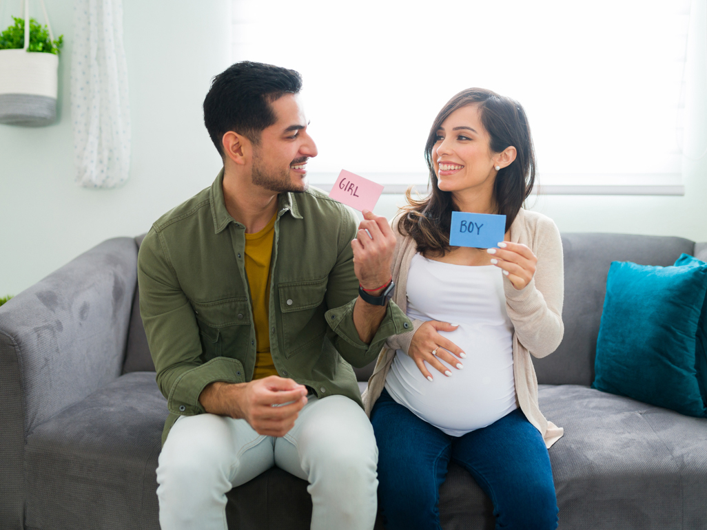 Man and woman holding up pink and blue cards 