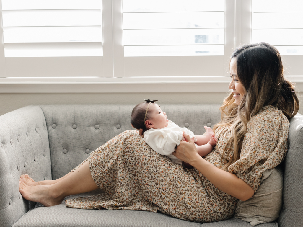 mom holding newborn baby on couch