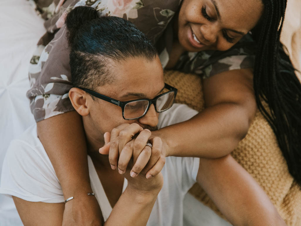 couple lying on the bed with their hands clasped together