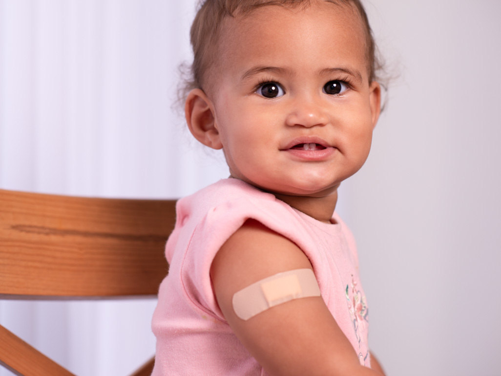 Child with a bandage on her arm smiling after the vaccination