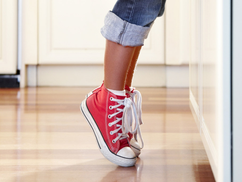 girl in red shoes standing on tiptoes