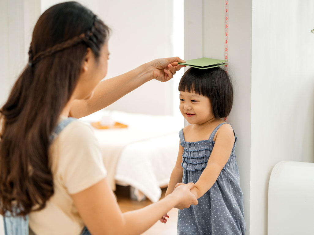 A mother measuring her child's height