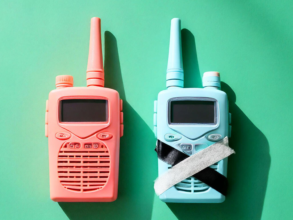 Two walkie talkies, one with tape covering the speaker