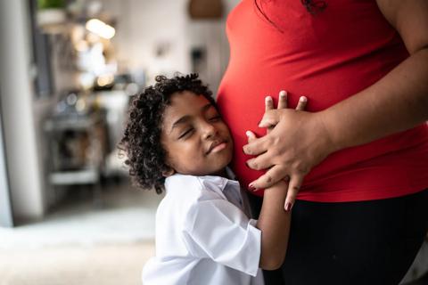 Child hugging pregnant mother