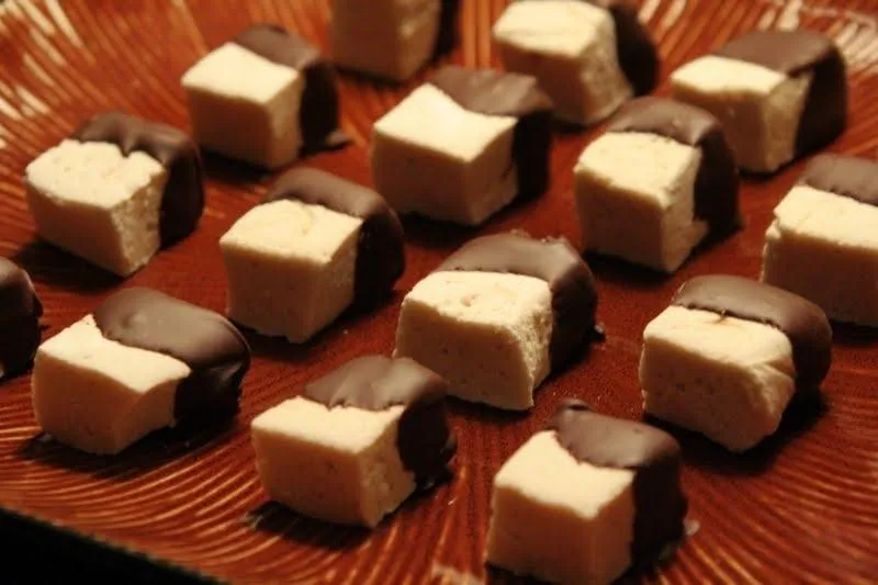 Chocolate-covered marshmallow squares arranged on a decorative plate.