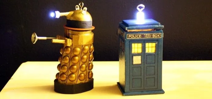 Dalek and TARDIS toy figures illuminated on a table.