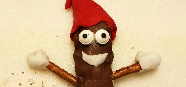 Chocolate treat shaped like a character with a red hat and pretzel arms.