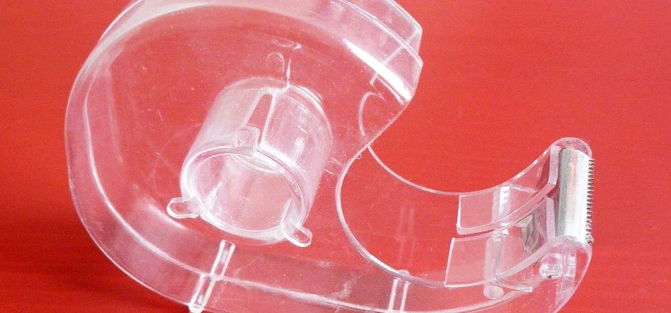 Transparent tape dispenser on a red background.