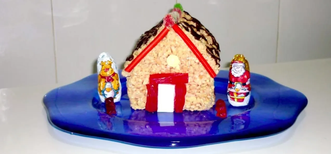 Christmas-themed decorative rice crispy house with colorful figurines.