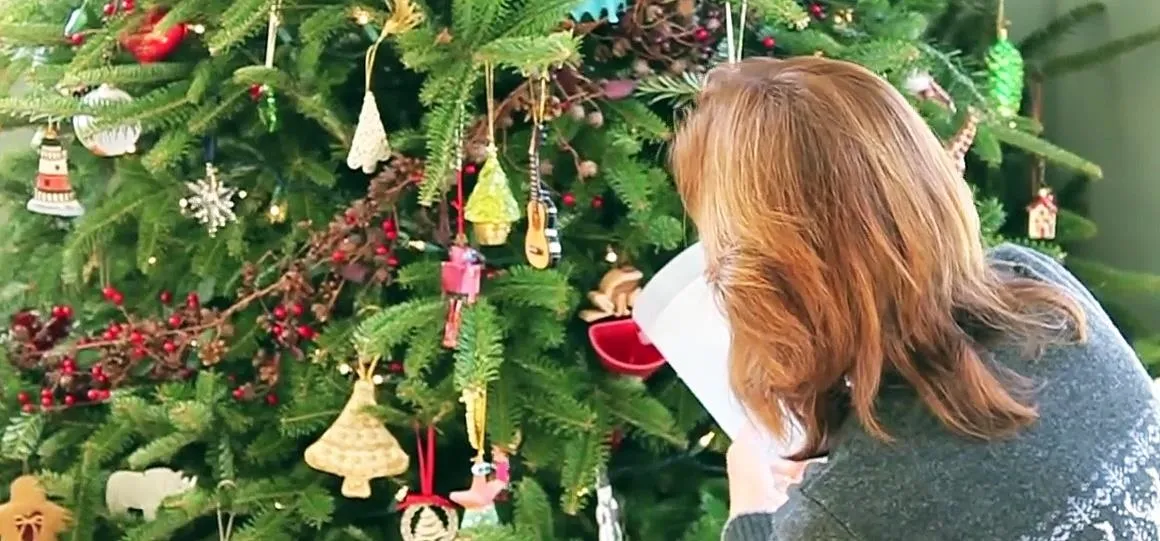 Person decorating a Christmas tree.