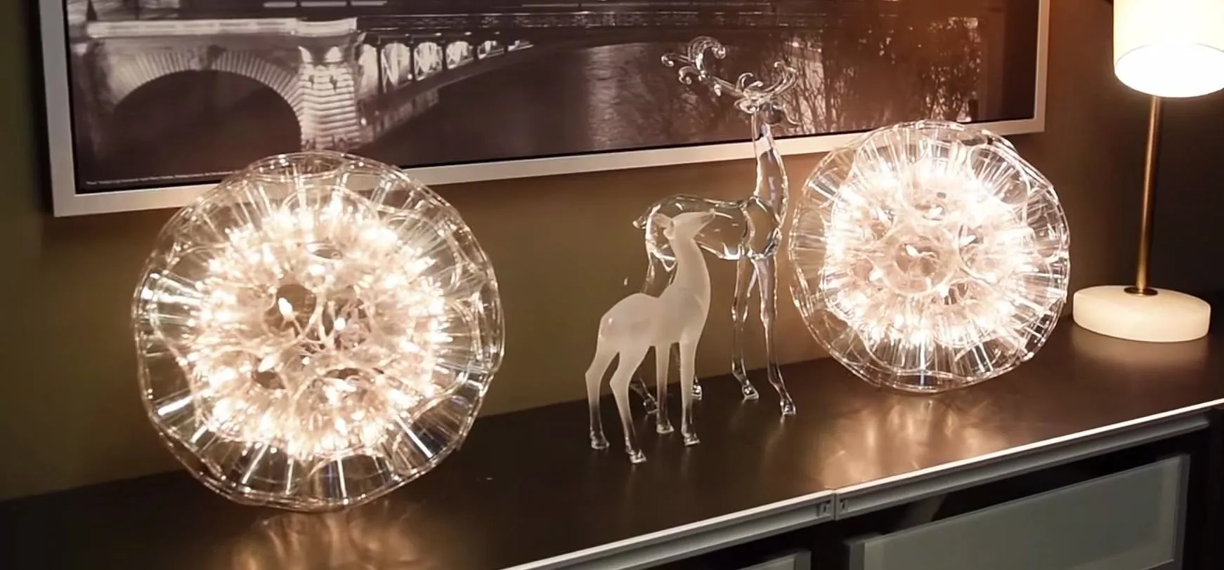 Decorative illuminated spheres and a transparent figurine on a shelf.