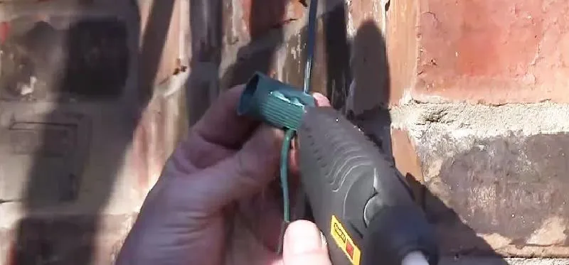 Hand holding a heat gun near a brick wall.