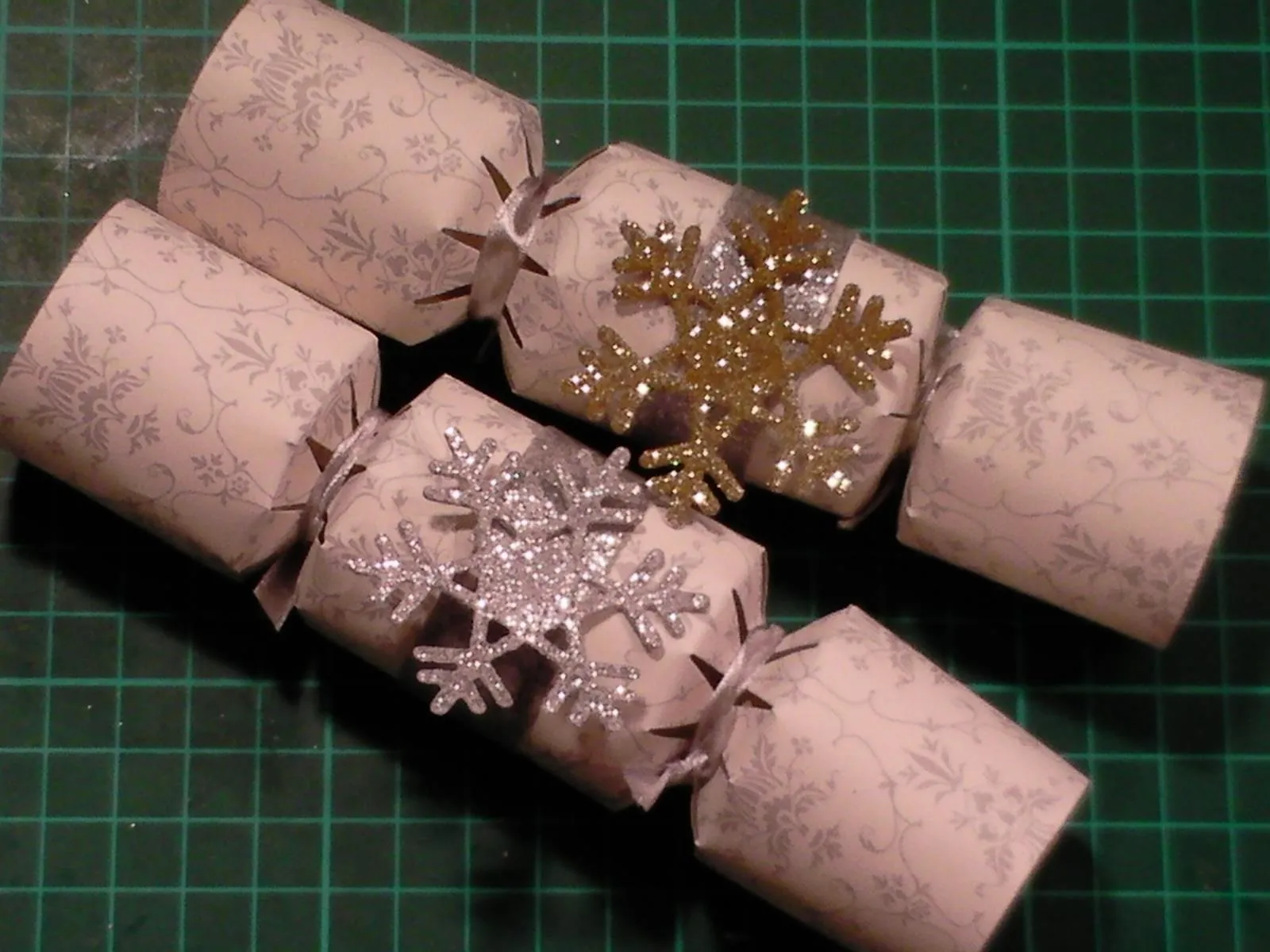 Festively decorated holiday crackers arranged on a green cutting mat.