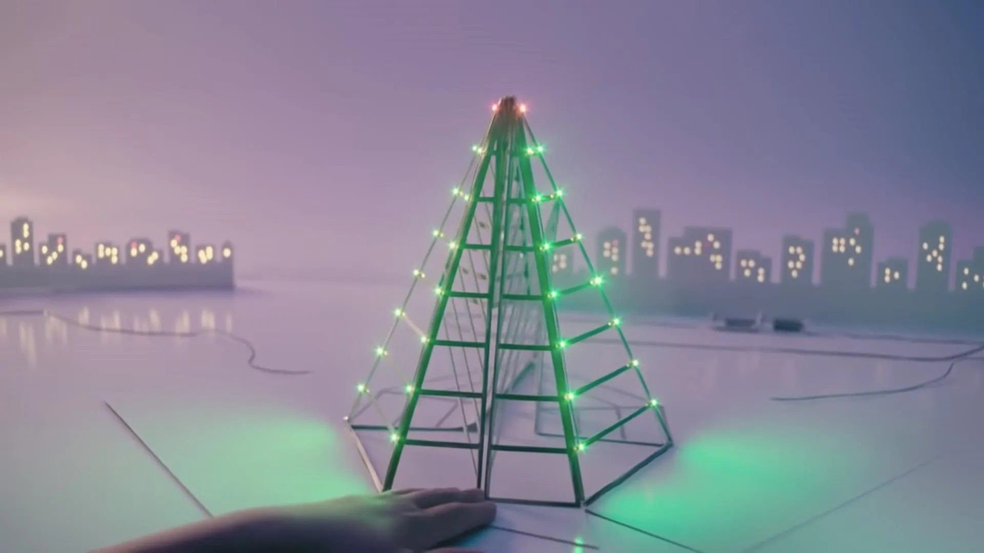 Miniature Christmas tree with colorful lights against a city skyline background.