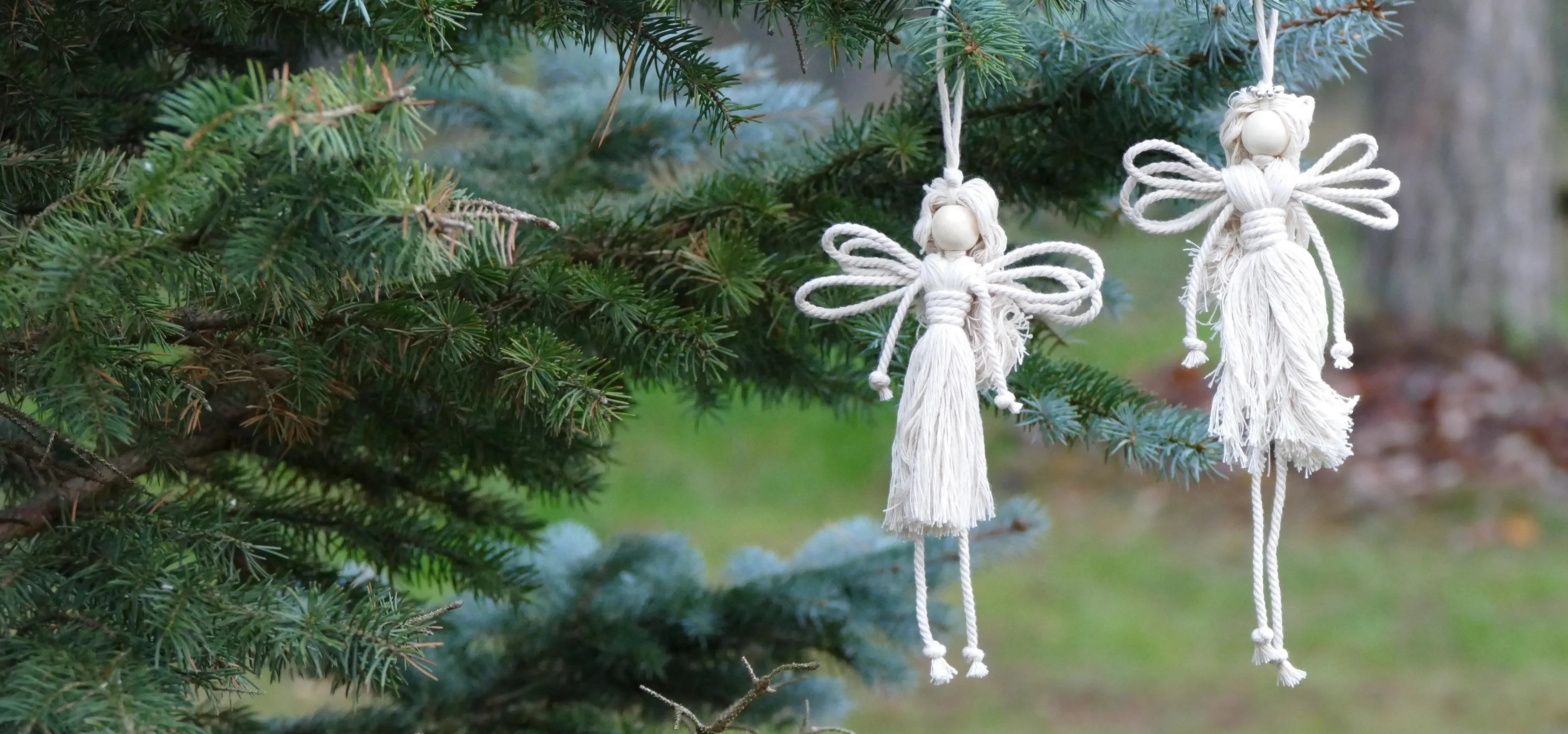 Handcrafted white fairy ornaments hanging from a tree branch.