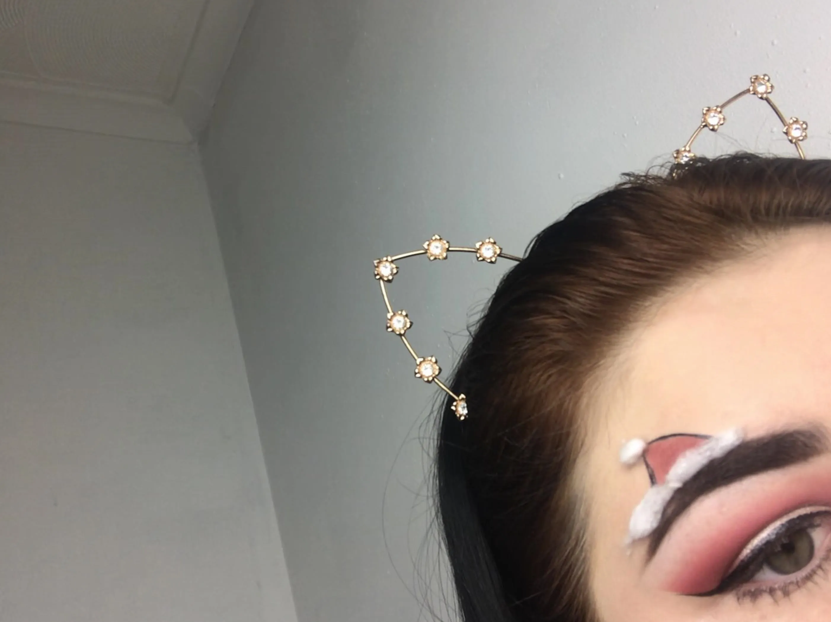 Close-up of a person's eye with dramatic makeup and decorative cat ear headband.