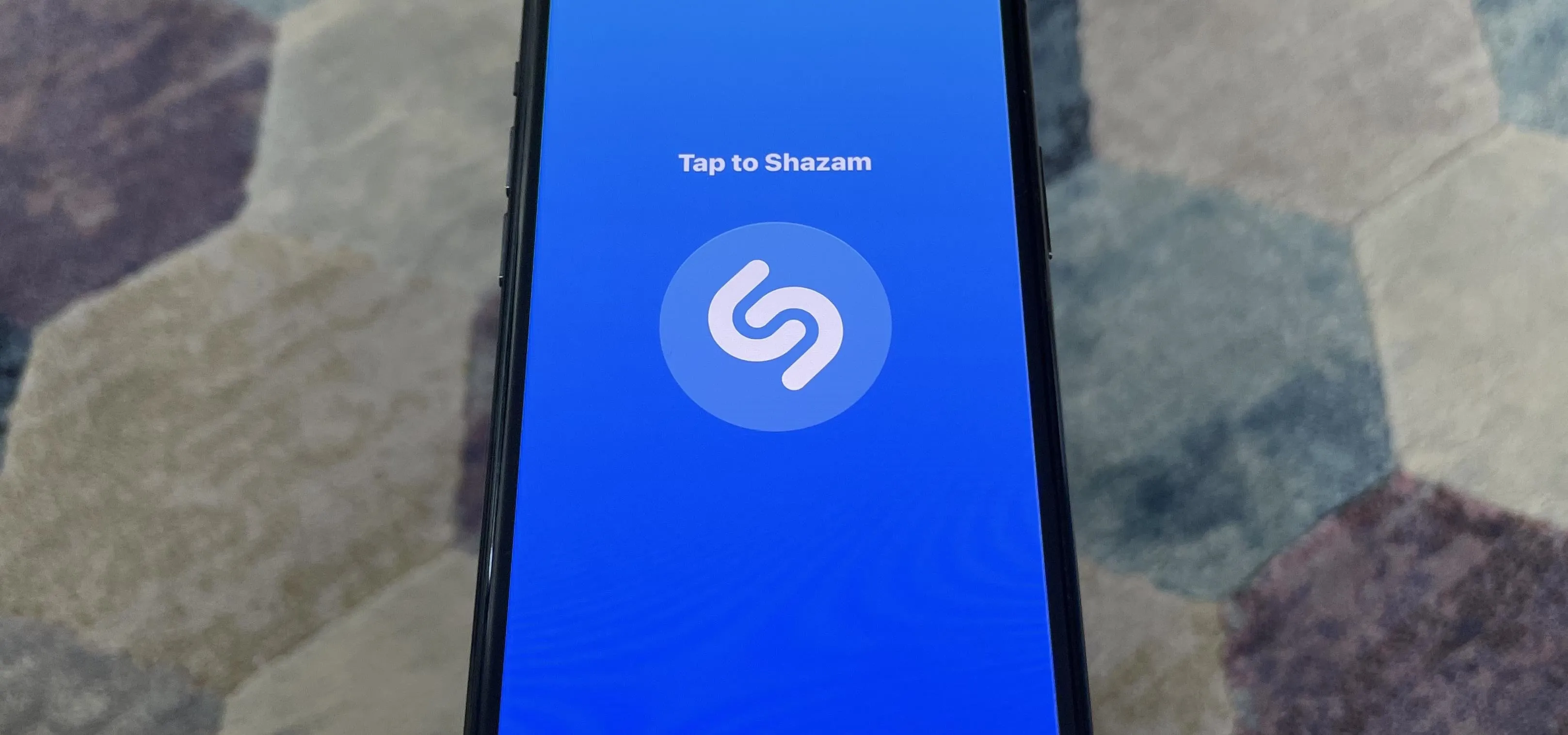 Smartphone displaying the Shazam app interface with a prompt to tap to listen.