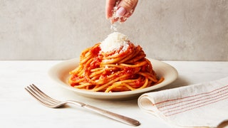 A serving of pasta pomodoro on a plate topped with grated cheese.