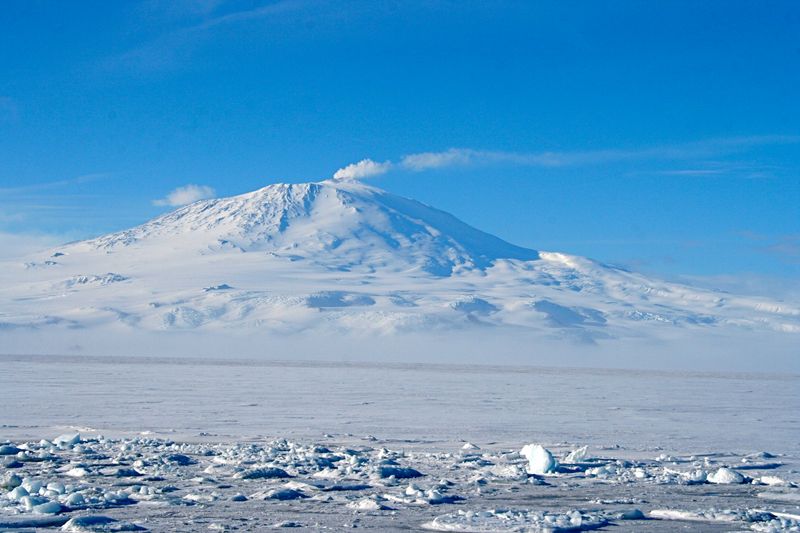 photo of Mount Erebus against clear blue sky with ice sheet in the foreground