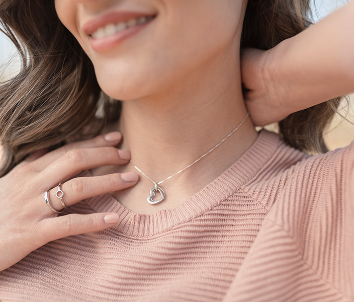 A woman trying on a heart pendant silver necklace