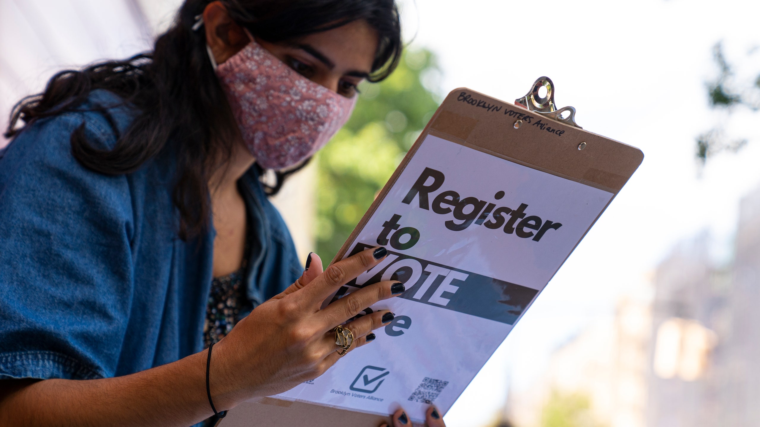 A volunteer from Brooklyn Voters Alliance checks a woman's application after she registered to vote September 27 2020 in...