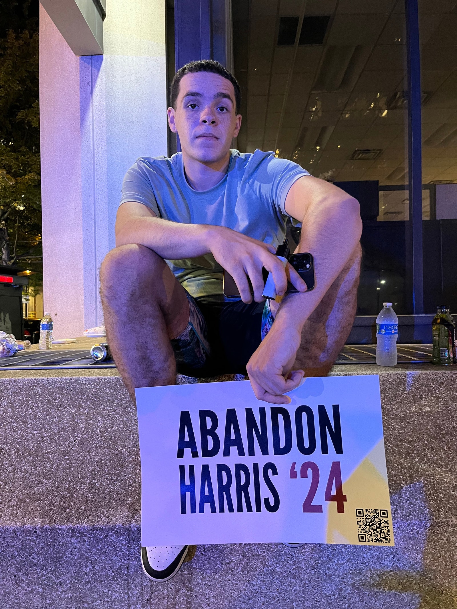 A bystander outside the 2024 presidential debate holds an “Abandon Harris '24” sign.