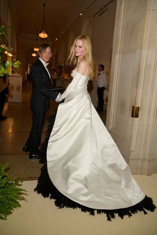 Image may contain Keith Urban Clothing Dress Formal Wear Fashion Gown Wedding Wedding Gown Suit Lamp and Plant