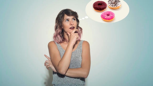 Young woman thinking about an assortment of donuts 