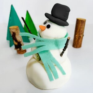 Our playdough snowman sitting in front of a miniature winter scene