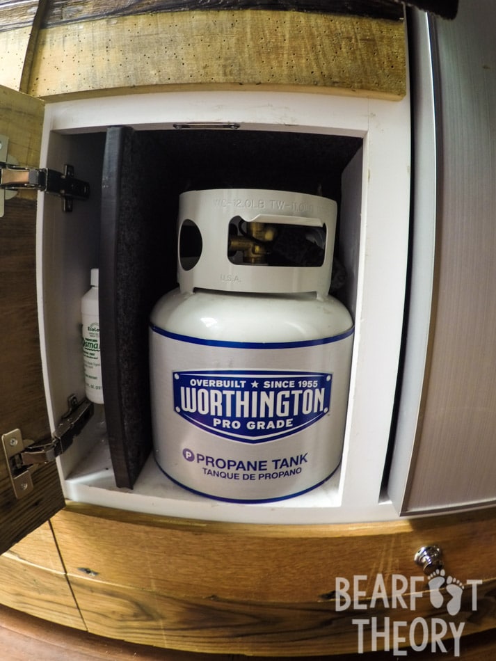 The 1 gallon propane tank is stored in a cabinet under the sink in Kristen's first Sprinter camper van which powers the dual propane burner in the galley