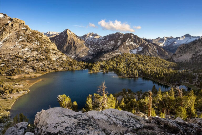 Mountains and trees juxtaposed next to a blue lake on the John Muir Trail