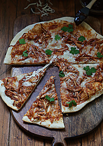 bbq turkey pizza on cutting board. Slices pulled from pizza.