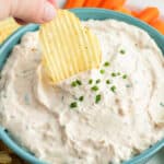 wavy potato chip being dunked into French Onion Dip