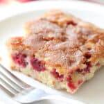 square piece of cranberry christmas cake on white plate with fork