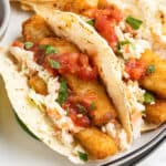 close up fish stick tacos with coleslaw and salsa on plate