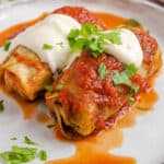 2 cabbage rolls on plate with tomato sauce and sour cream