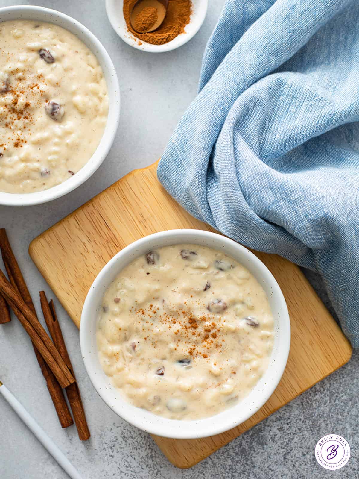 overhead of rice pudding in white bowls with cinnamon sticks