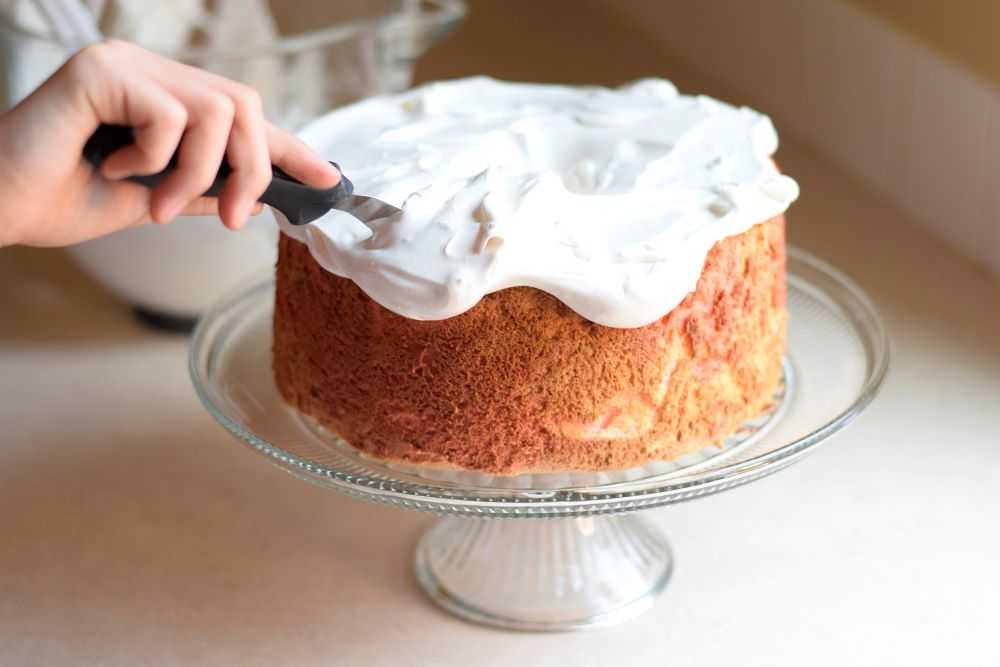 Frosting a cake with fluffy white frosting