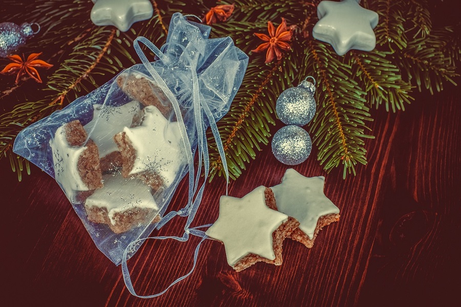 Dairy Free Holiday Cookies Close Up of Star-Shaped Gingerbread Cookies with Icing and Pine Tree Branches in the Background