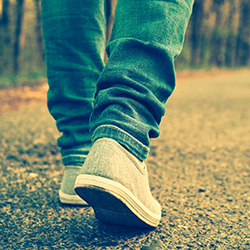 A person’s shoes while they walk down a road, representing 10,000 steps challenges as a fundraiser idea.