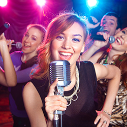 Four people singing with microphones at a karaoke night fundraiser.