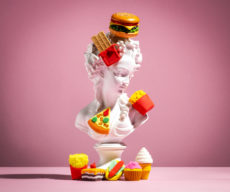 Plaster statue of woman pasted with miniature fast food on pink background. Unhealthy food diet poster.