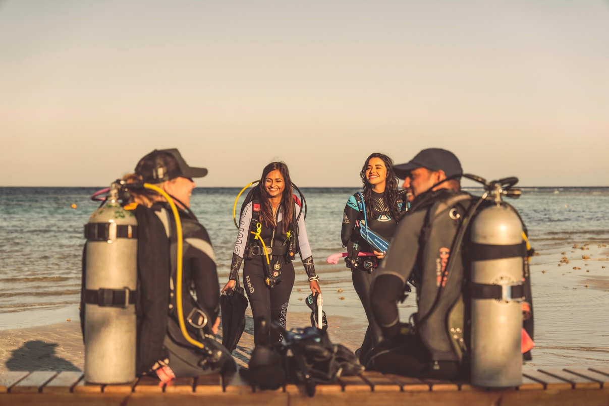 four divers smile at each other while preparing for a shore dive in Egypt