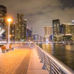 City buildings with lights near a body of water.