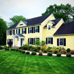 bLACK PANEL SHUTTERS ON YELLOW HOME