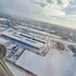 snowy airport seen out the window of a plane flying above