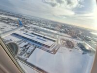 snowy airport seen out the window of a plane flying above