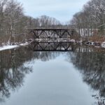 snowy river crossed by a trestle bridge in the distance