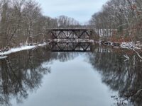 snowy river crossed by a trestle bridge in the distance